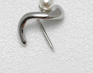 Detail view of a silver-colored metal hair clip featuring a minimalist pearl embellishment
