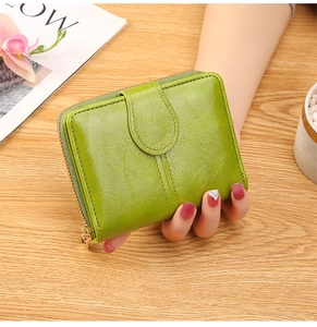 Close-up of a green faux leather short wallet with gold zipper and snap button closure