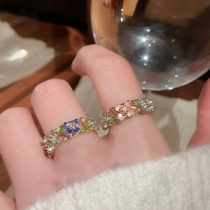 Detail of vintage enamel flower rings with crystals on model's finger in warm setting