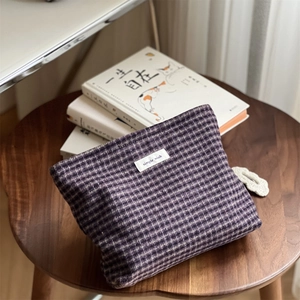 Detailed texture of a vintage purple plaid cosmetic bag on a wooden table setup