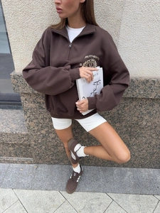 Street style view of deep brown oversized half-zip sweatshirt with white athletic shorts