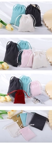 Close-up of velvet drawstring jewelry pouches in various colors with elegant silk backdrop