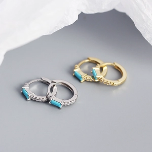 Macro detail of S925 silver hoop earrings with emerald green zircon and cubic zirconia