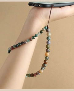 Detail of beaded phone wrist strap with agate-style stones on a black phone case