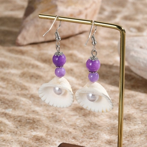 Detail view of purple beads and natural seashell earrings with pearls on gold hooks