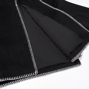 Vue détaillée de la couture en zigzag blanche sur le bord du manteau noir