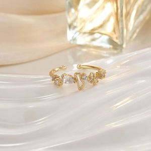 Close-up of a gold open ring with crystals on white silk fabric with elegant lighting