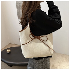 Détail du sac cabas en toile avec nœud en cuir élégant et bordure marron contrastée