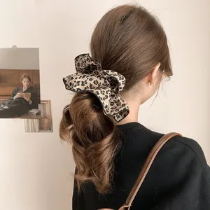 Detail of leopard print scrunchie with black trim on brown wavy hair for women