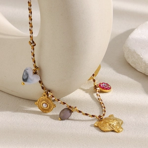 Detailed view of 18K gold leopard head, heart agate and pearl charms on braided rope
