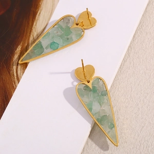 Macro detail of 18K gold heart earrings featuring light green crushed stone inlay