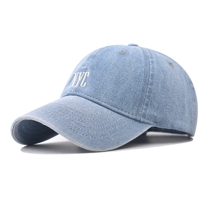 Detailed close-up of white NYC embroidery on vintage washed denim baseball cap