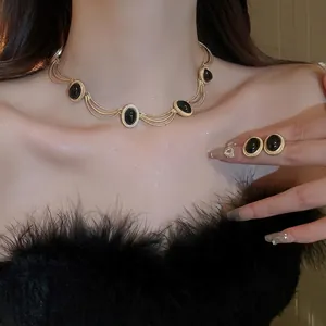 Vintage gold necklace and earrings set with oval black gemstones on elegant model