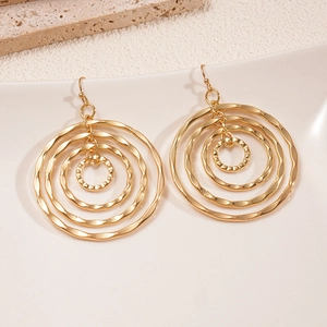 Golden multi-layer hollow circular textured geometric drop earrings on white ceramic