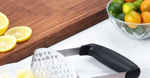 Gros plan du presse-purée en acier inoxydable avec poignée noire sur un plan en marbre