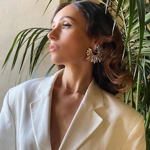 Chic oversized colorful crystal C-shaped hoop earrings worn by a model in linen blazer