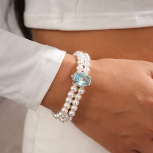 Close-up of double-layer pearl bracelet with a large light blue gemstone centerpiece