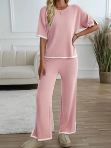 Detail of pink knitted set showing short-sleeved top and wide-leg pants with white piping