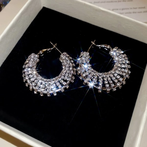 Detailed view of silver hoop earrings with shimmering rhinestones on black velvet