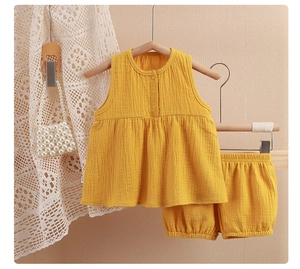 Detail of yellow cotton gauze sleeveless baby set with textured fabric and wood buttons