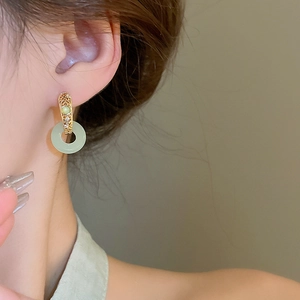 Detailed close-up of vintage gold plated jade hoop earrings on a model profile view