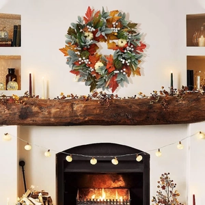 Detail view of fall wreath with white pumpkins and maple leaves on a white wall