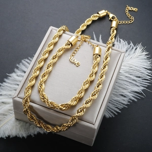 Detail of 18K gold-plated 6mm rope chain necklace and bracelet set on a gray gift box