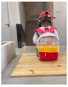 Detail showing colorful patchwork canvas backpack with red grid pattern for kids