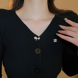 Détail de broches nœud et C entrelacé dorées élégantes sur un vêtement en maille noir