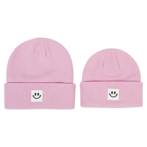 Dettaglio di berretti in maglia rosa con toppa smiley per genitori e bambini
