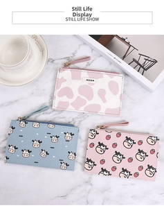 Flat lay of cute cow print leather coin purses with zipper and wristlet on marble background