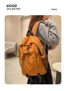 Detail eines karamellfarbenen Nylon-Rucksacks mit Kordelzug-Fronttasche und Netz-Seitentaschen