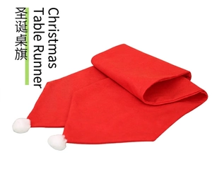 Macro shot of red Christmas table runner with white fluffy pom-pom decorations