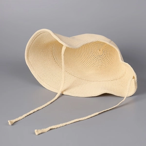 Close-up of cream knitted sun hat featuring circular weave texture and adjustable ties