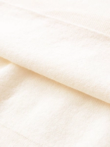 Detailed macro view of the soft beige knitted fabric texture and fine ribbed weave