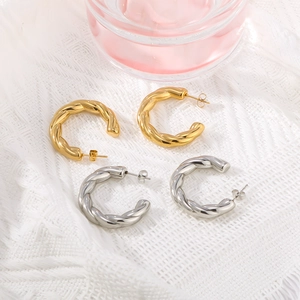 Textured C-shape twist hoop earrings in gold and silver finish on white fabric
