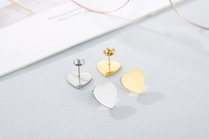 Detailed view of polished heart-shaped stud earrings in gold and silver stainless steel