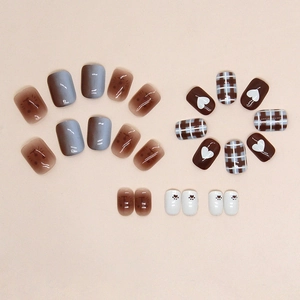 Détail de faux ongles marron chocolat avec motifs cœur, écossais et pattes de chat