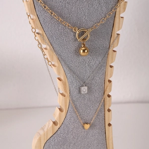 Detailed display of layered gold and silver necklaces on a wood and velvet jewelry stand