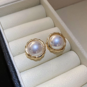 Gros plan de boucles d'oreilles perles avec bords dorés texturés dans un écrin en velours