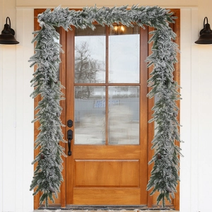 Detailed view of snowy flocked Christmas wreath with natural pinecones on a front door