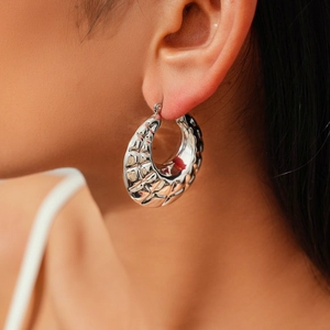 Close-up of silver textured hoop earrings featuring a vintage geometric lattice pattern