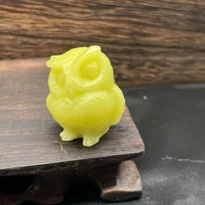 Close-up of a 3.5cm translucent green natural stone owl figurine on a wooden base