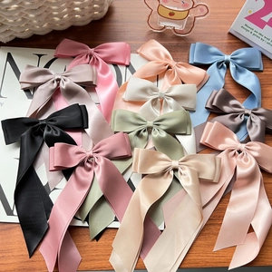 Flat lay of colorful satin double-layered bow hair clips with long ribbons on wooden desk