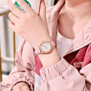 Gros plan sur la montre rose avec lunette diamantée en or rose au poignet d'une femme