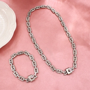 Silver H-link necklace and bracelet set with crystal inlay on pink silk background