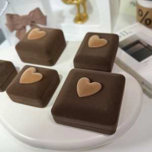 Macro detail of velvet jewelry boxes in dark coffee with heart-shaped lid accents