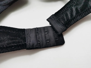 Detailed macro view of black velvet push-up bra featuring double hook-and-eye back closure