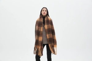 Detail of soft brown and beige plaid scarf with tassels on a full-length model
