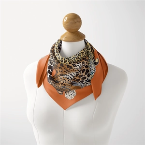 Close-up of silk square scarf featuring leopard print and vibrant orange border detailing